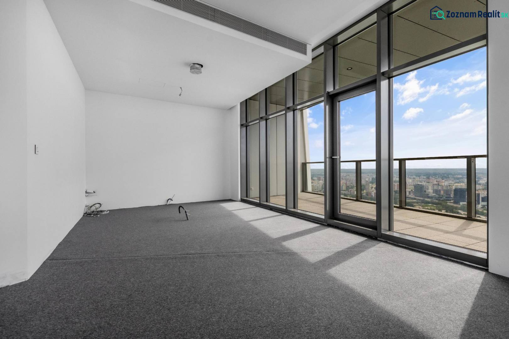 A room with large windows and a view from a 4-room apartment, covered with carpet.