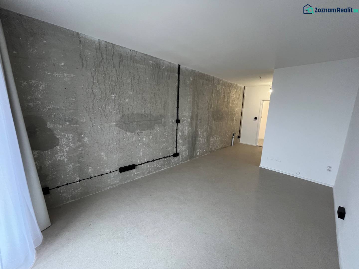 Studio apartment with concrete wall and floor, bright minimalist interior.