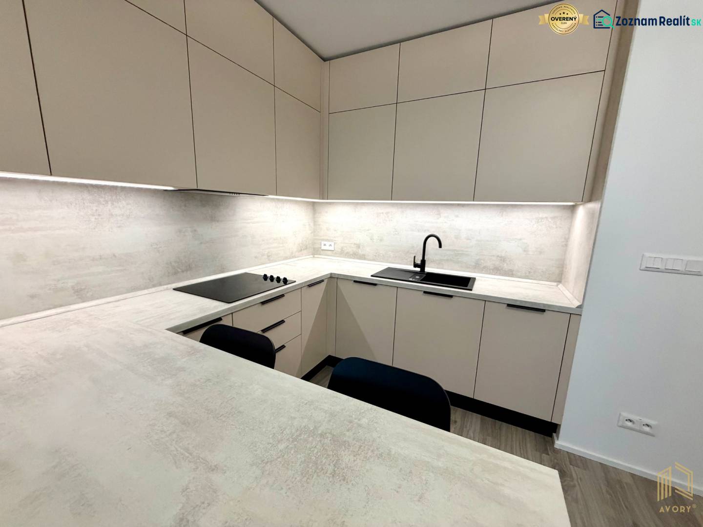 A kitchen unit with subtle lighting and a wooden decor floor in a studio apartment.