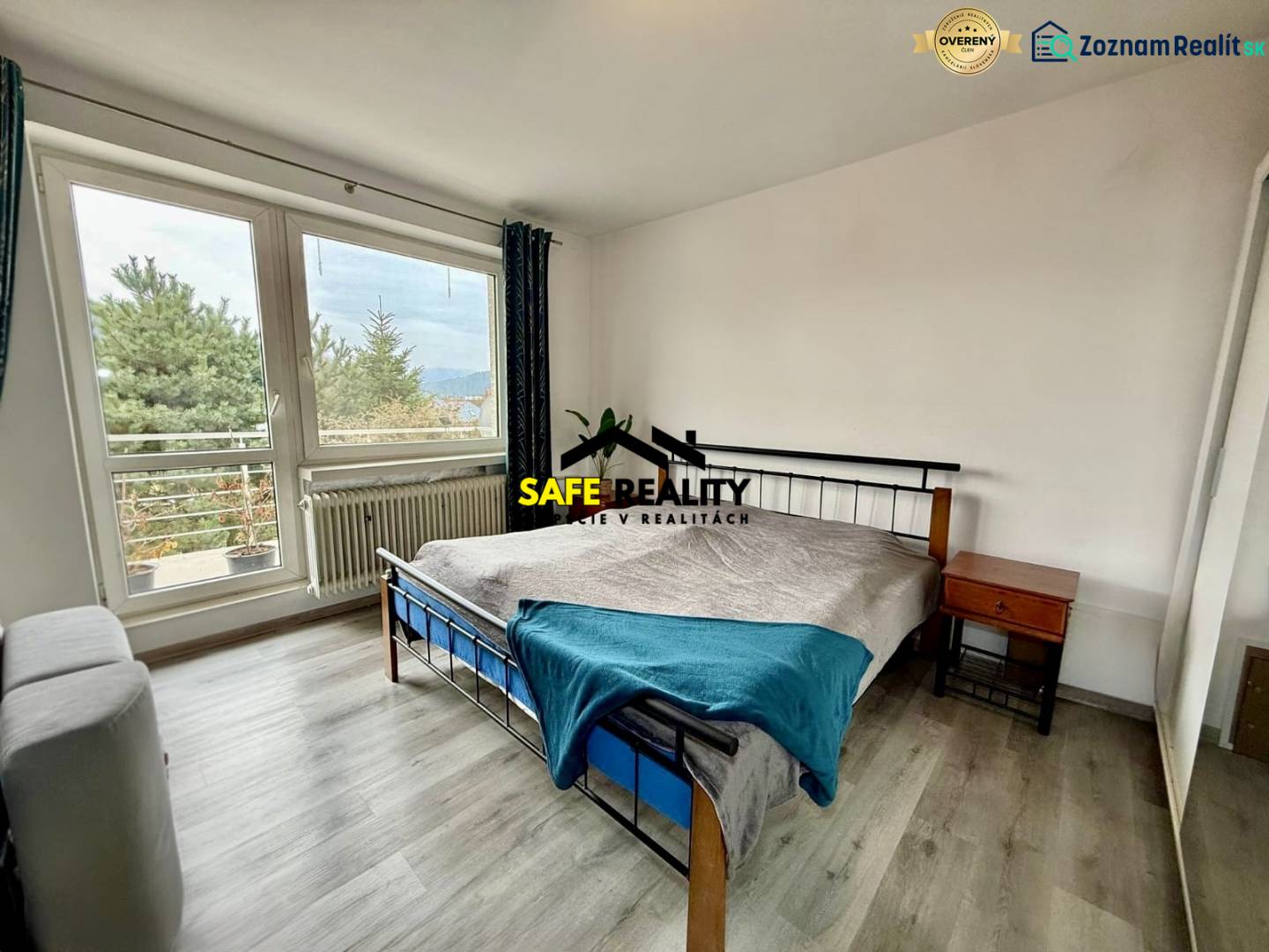 A bedroom in a family house with a wooden decor floor and large windows.