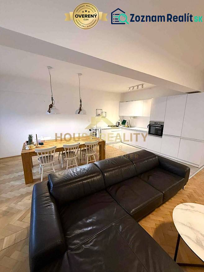 Living room with kitchen in a 4-room apartment, wooden decor flooring, spacious sofa and dining table.