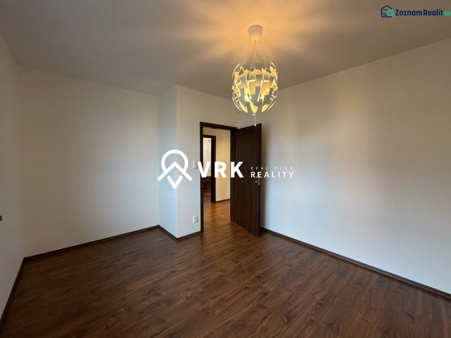 A room in a family house with white walls and a wooden decor floor.