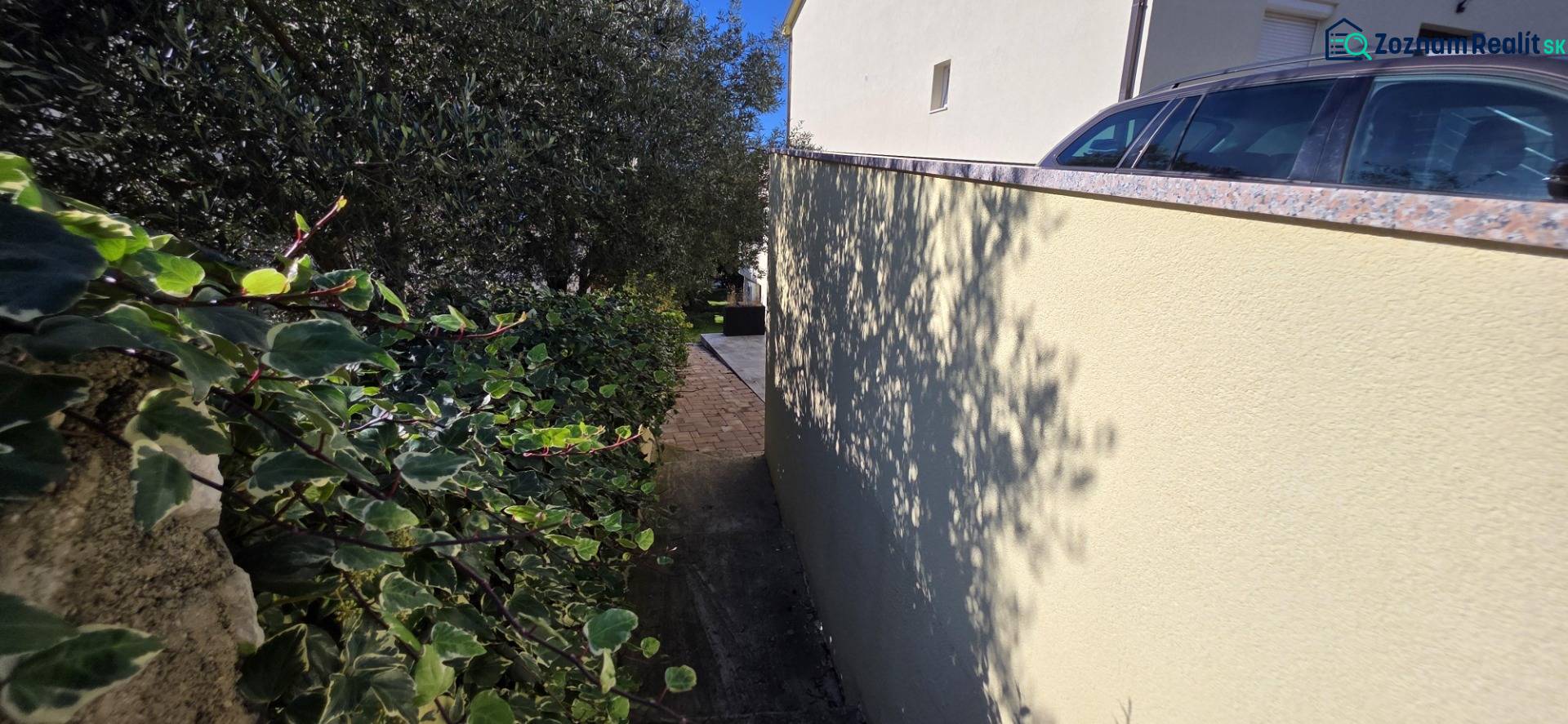 A narrow alley between the house and greenery in Crikvenica, suitable for pleasant walks.