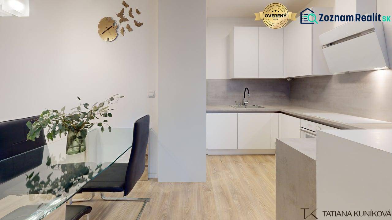 A kitchen in a 3-room apartment with a glass table and a floor with a wooden decor.