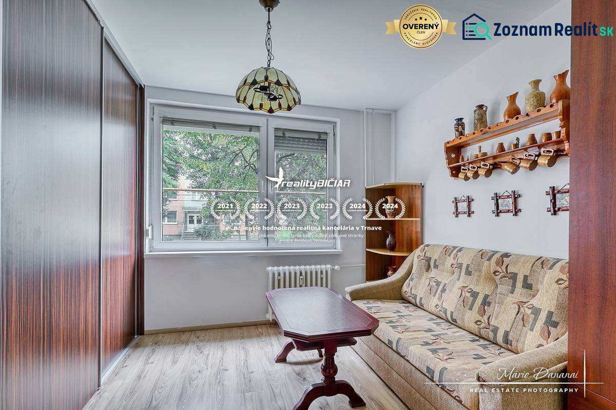 A room in a 3-room apartment with a sofa, a table, and a floor with a wooden decor.