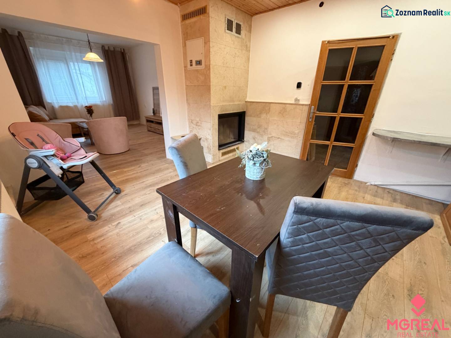 Dining area with a solid wood table, fireplace, and wooden decor flooring in a family house.