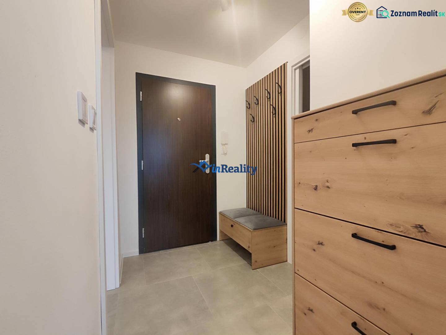 Hallway with a coat rack and a dresser in a studio apartment, wood-patterned flooring.