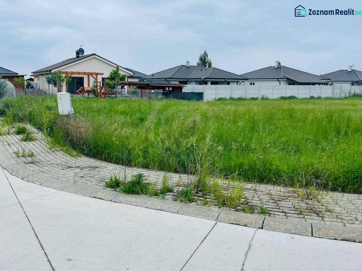 Plots - housing on Podháj Street in Hviezdoslavov, with grassy areas and family houses in the background.