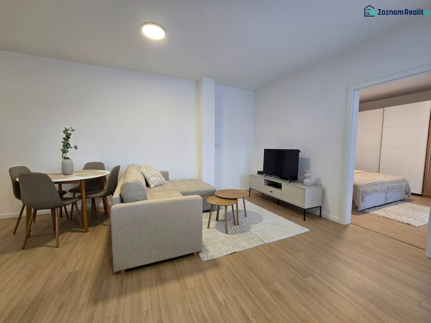 Living room of a 3-room apartment with a wooden decor floor, a sofa, and a dining table.