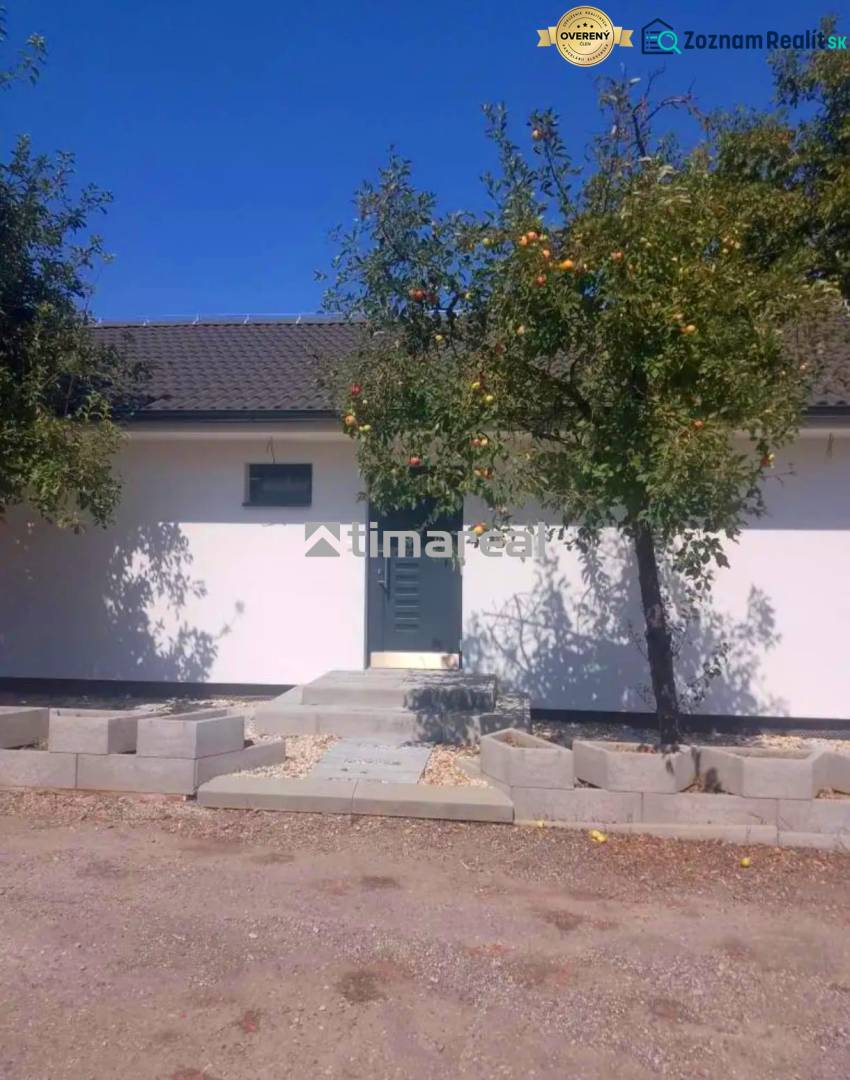 A family house in Kaplna with apples on the tree and a clear sky.