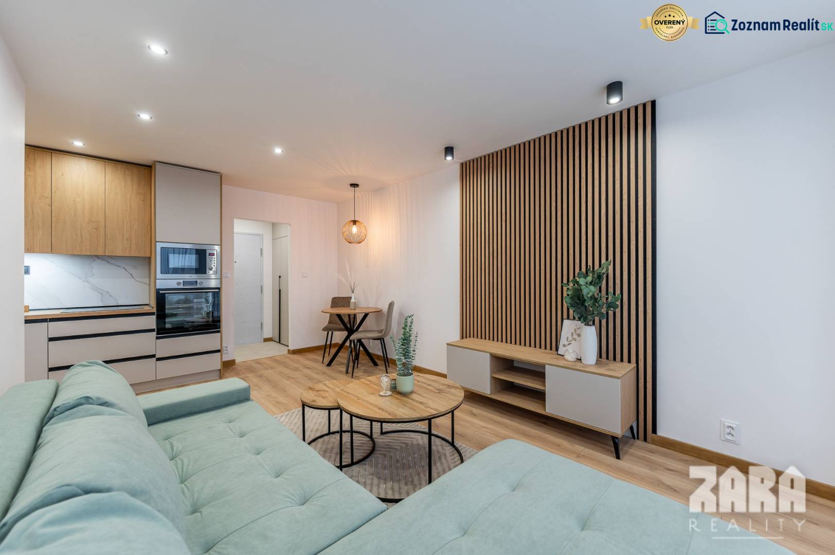 Living room in a two-room apartment with a kitchenette and a wooden decor floor.