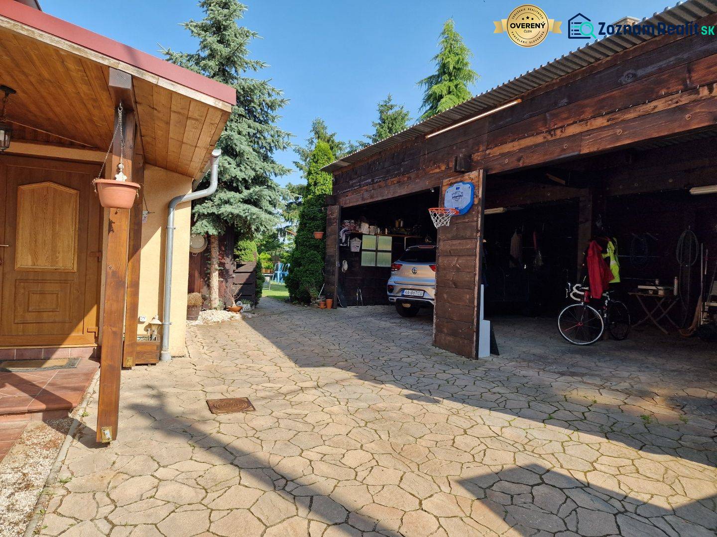 A family house in Dlhá nad Váhom with a shelter, garage, and landscaped yard.
