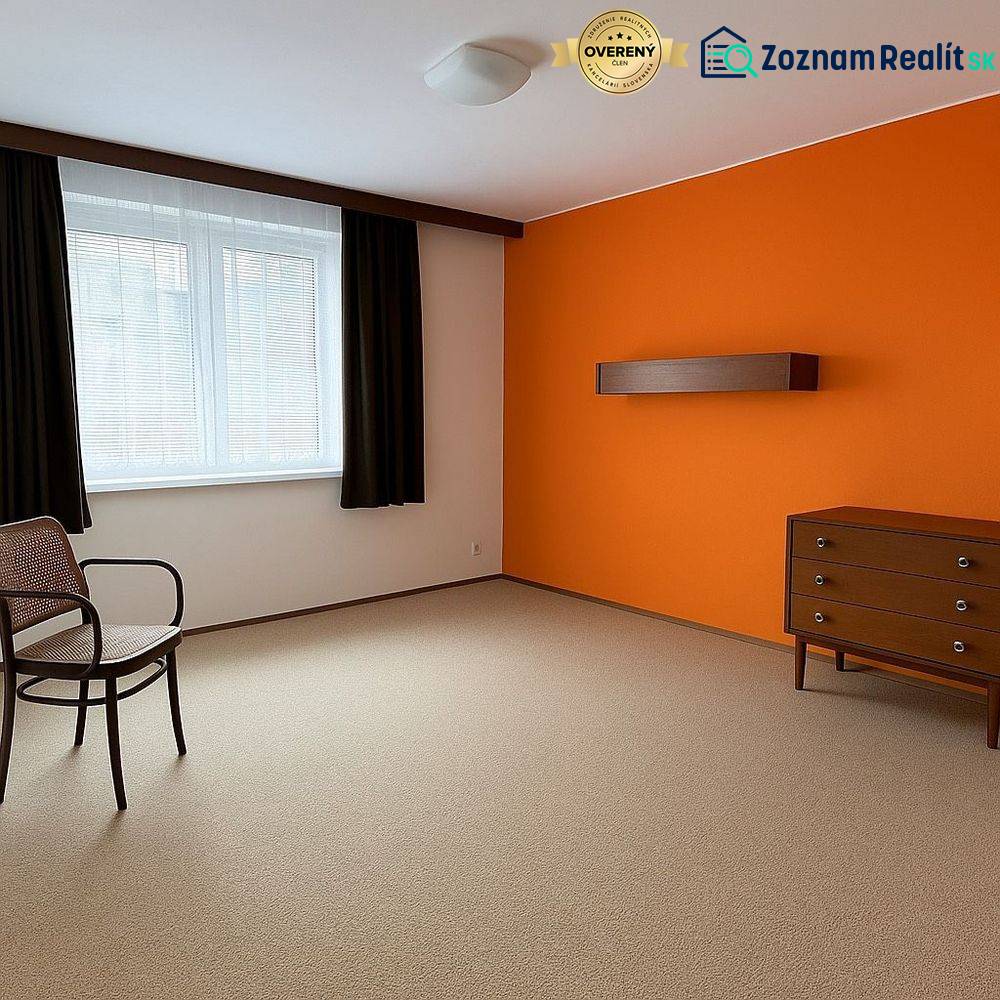 A room with an orange wall, furniture, a window, and carpeted flooring in a family house.