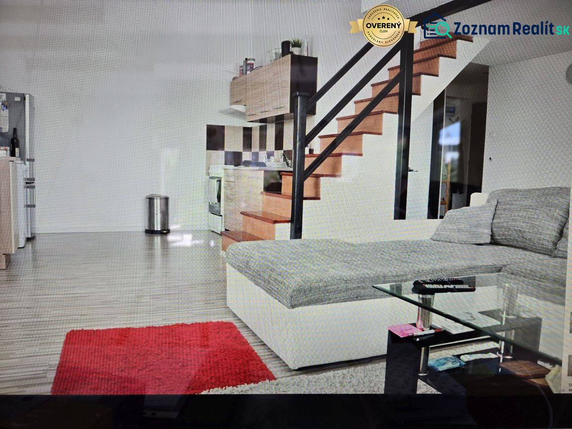 Living room with a kitchenette, staircase, sofa, glass table, and wooden decor flooring.