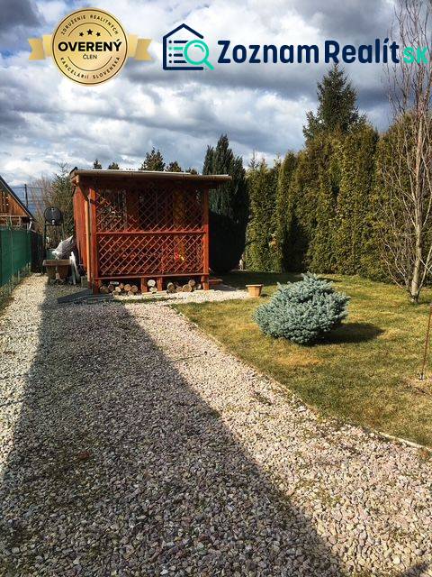 Wooden cottage in Kráľová nad Váhom with a landscaped garden and a bush.