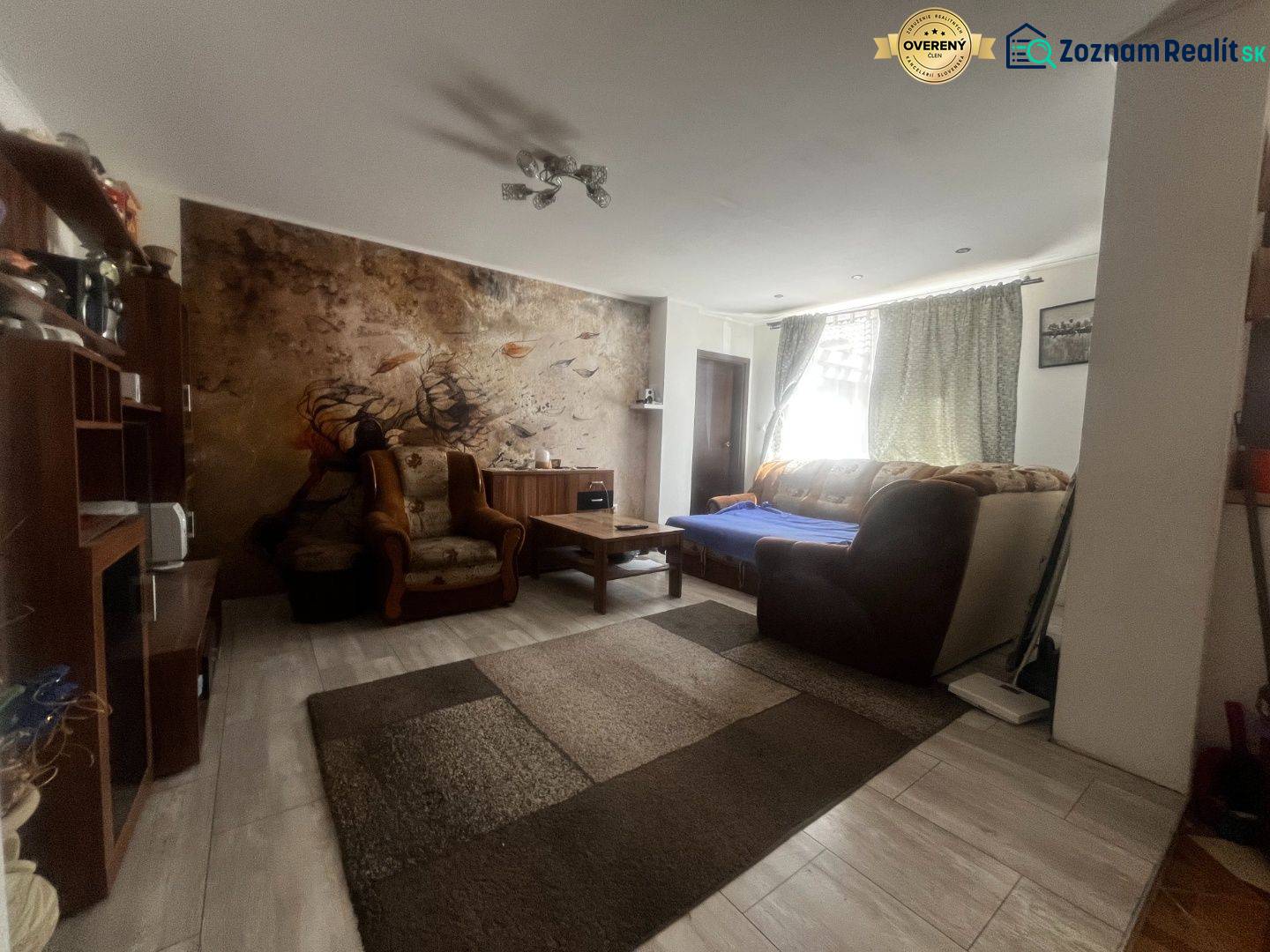 Living room in a family house with a sofa, armchairs, and a mural behind the seating area.