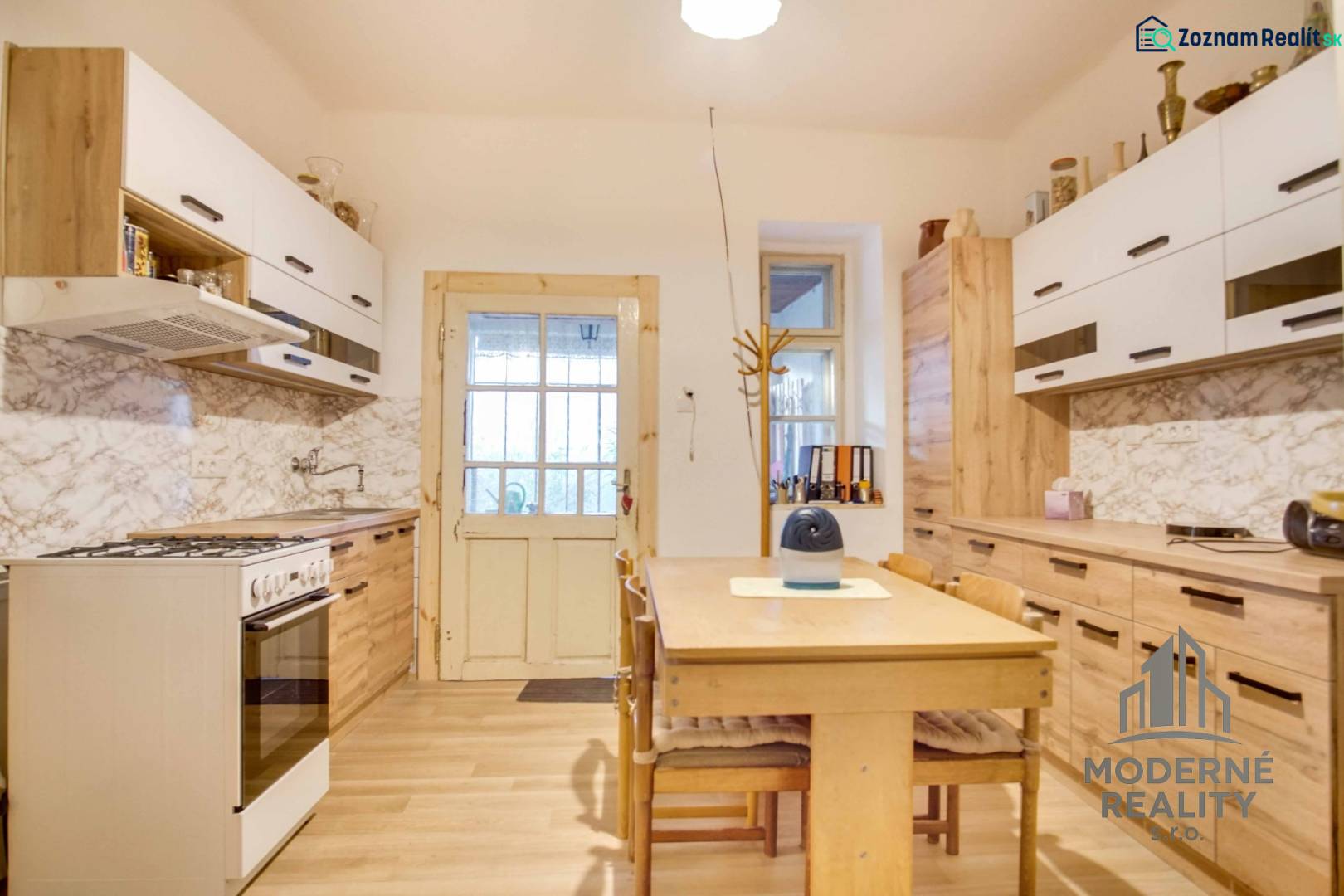 A kitchen in a family house with a wood-patterned floor and white cabinets.