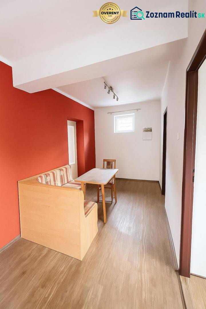 A dining room in a family house with a red wall and a wooden decor floor.