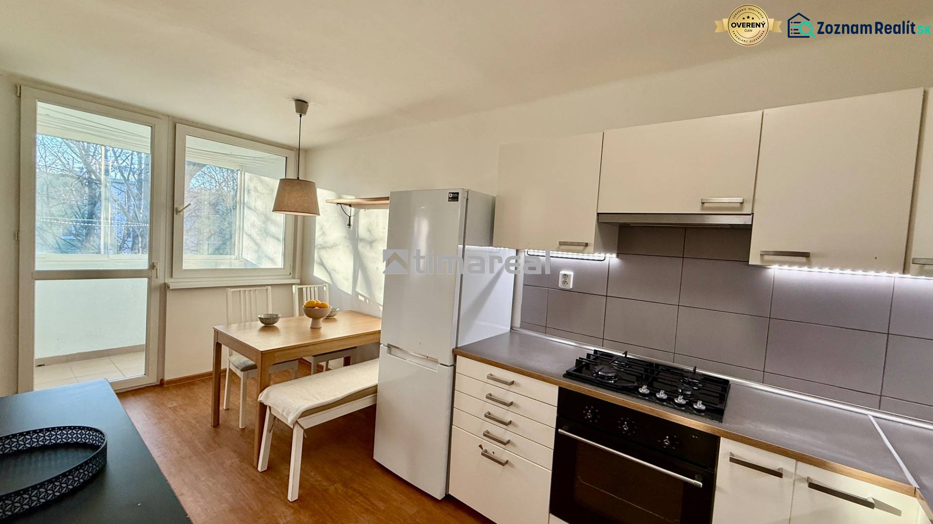 A kitchen in a 3-room apartment with a dining table and a floor with a wooden decor.