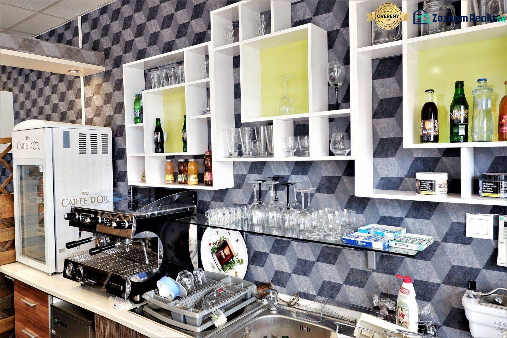 Interior of commercial space with a coffee machine, shelves, glasses, and drinks on the shelves.