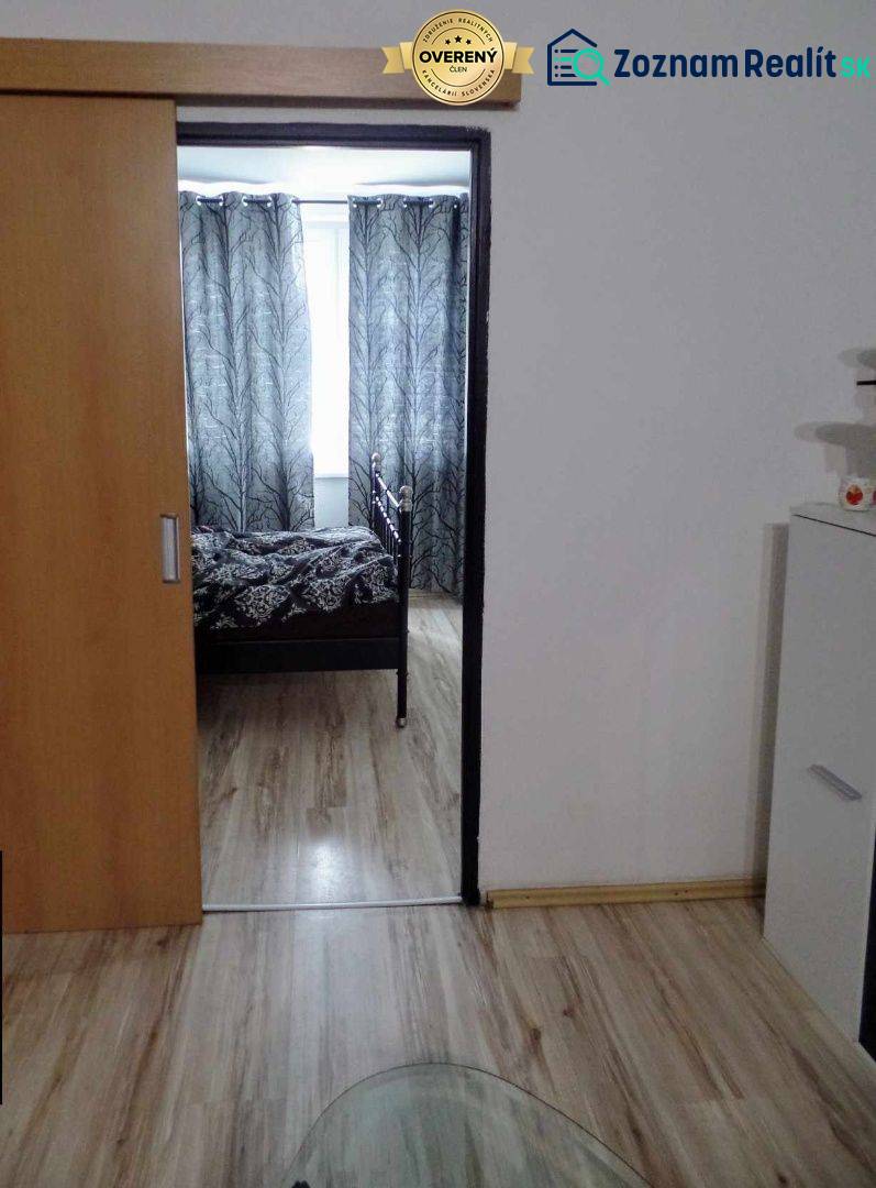 Interior with wood-patterned flooring, sliding doors, and black-and-white curtains in a 3-room apartment.