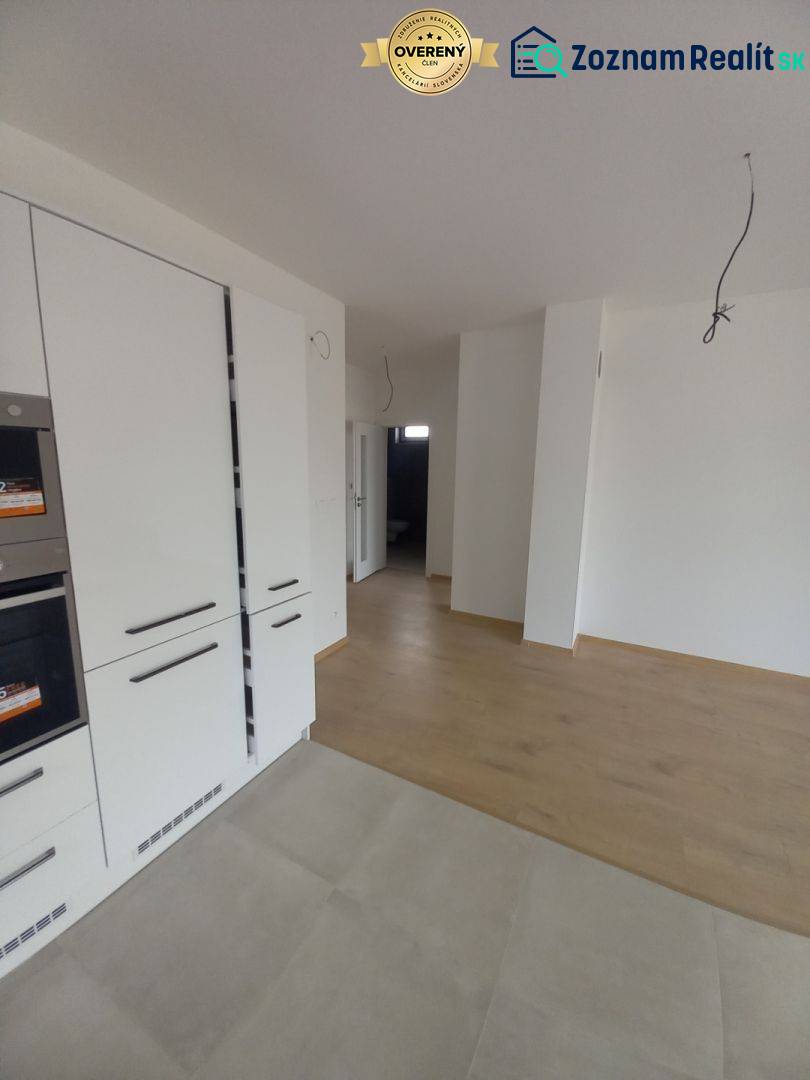 The kitchen area of a family house with white cabinets and a floor with a wooden decor.