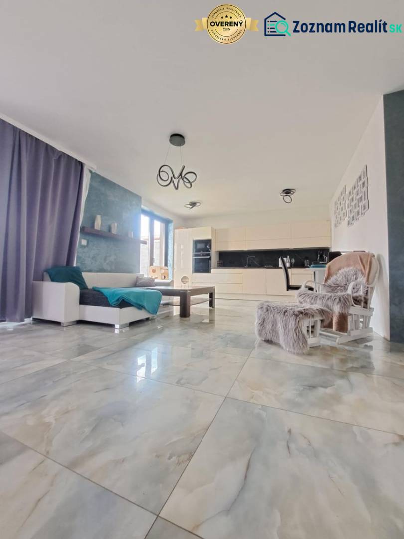 Living room with large windows and light tiles in a family house.