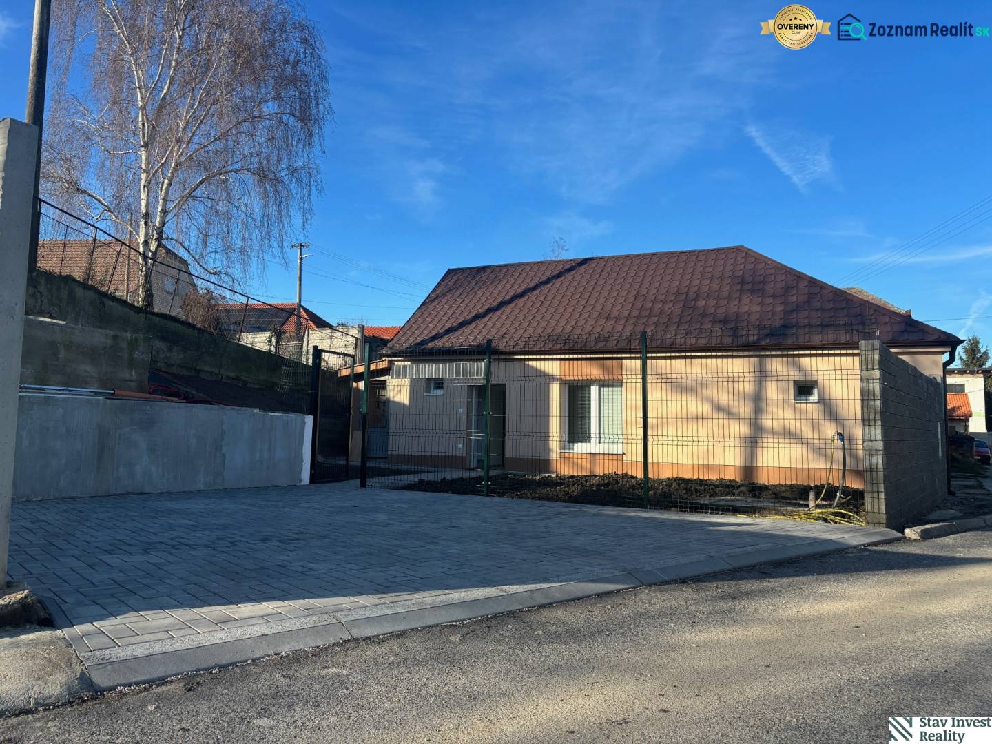 A family house in Blatné with a brown roof, a paved parking area, and a concrete fence.