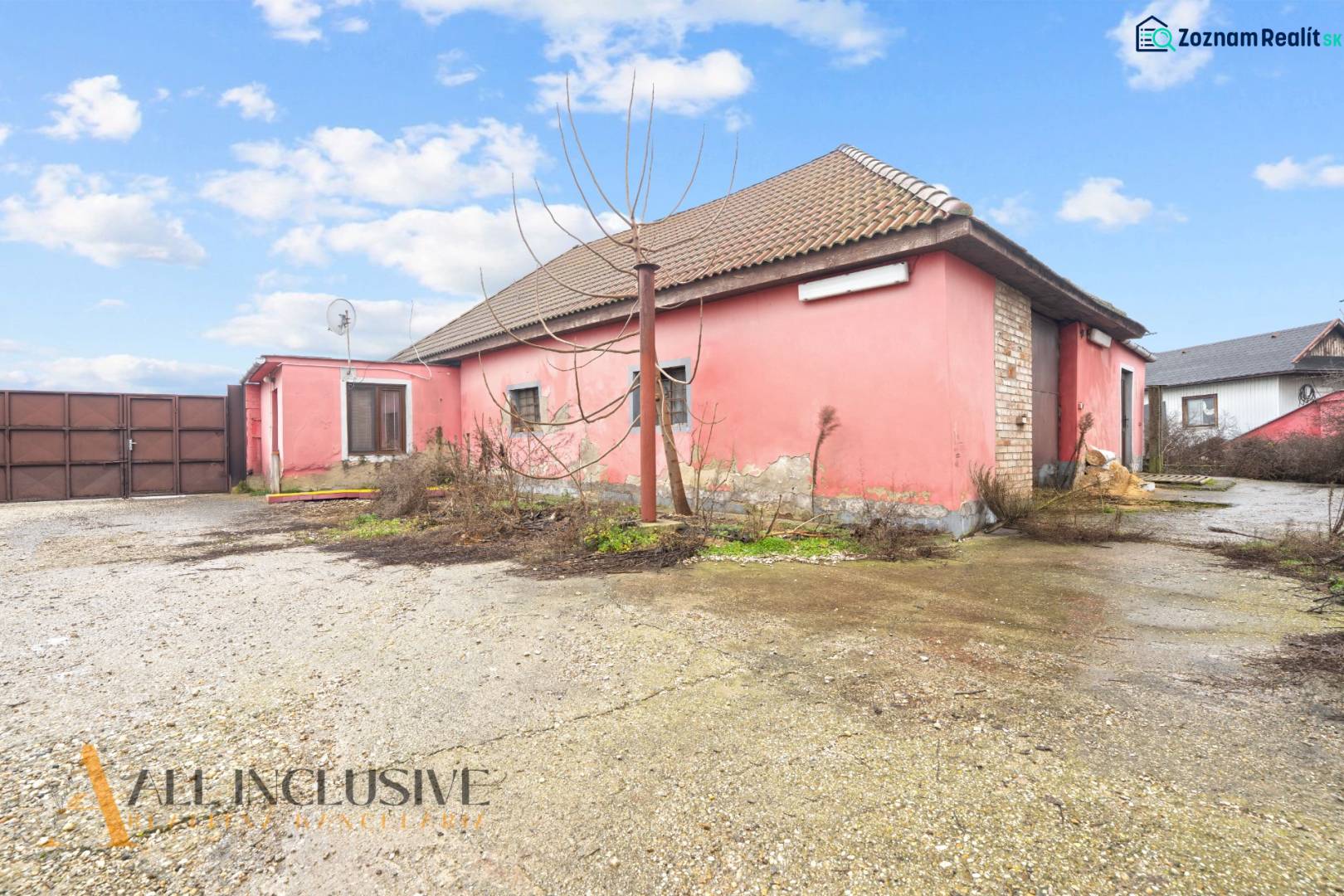 A family house in Šintava with a pink facade, a sloped roof, and a spacious yard.