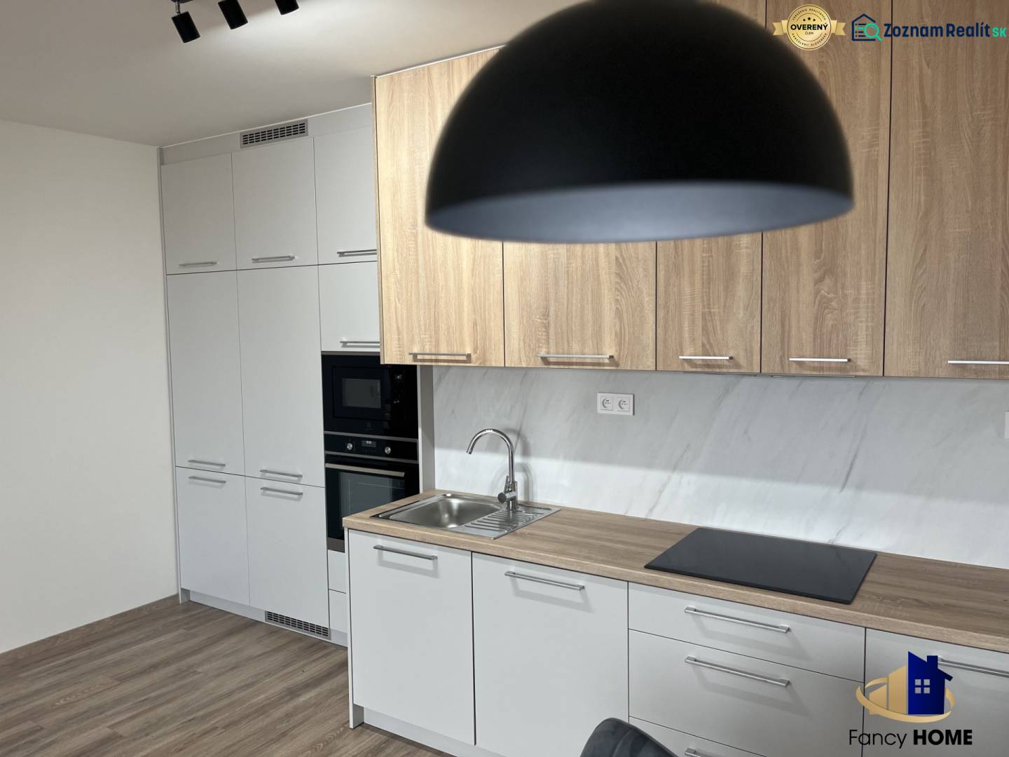 A kitchen in a two-room apartment with a wooden decor floor and light furniture.