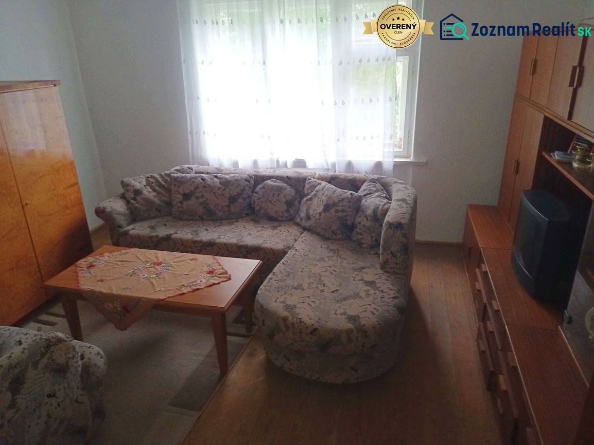 Living room in a family house with a corner sofa and a table on a floor with a wooden decor.