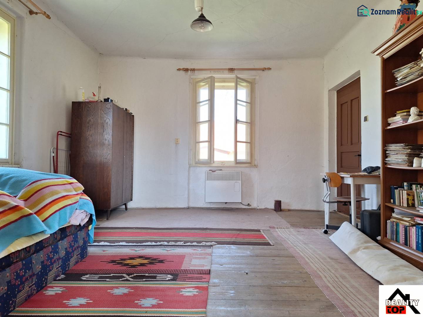 A room in a family house with carpets and a bookshelf, floor with wooden decor.