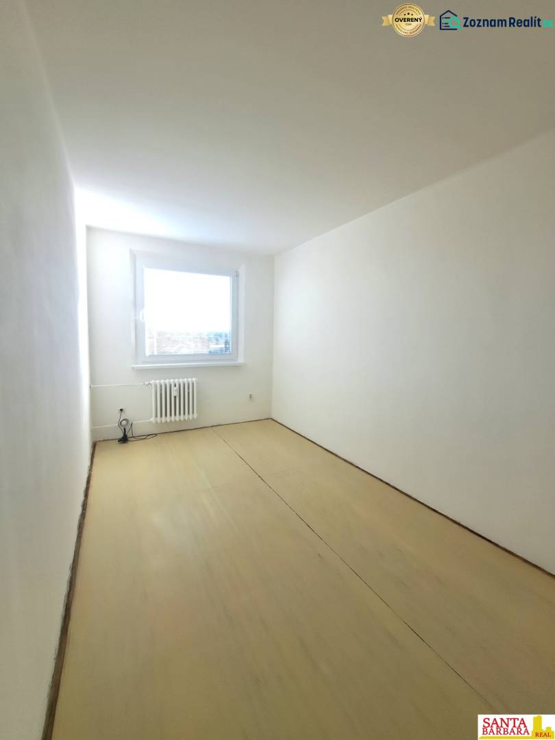 A room in a 4-room apartment with white walls and a wooden decor floor.