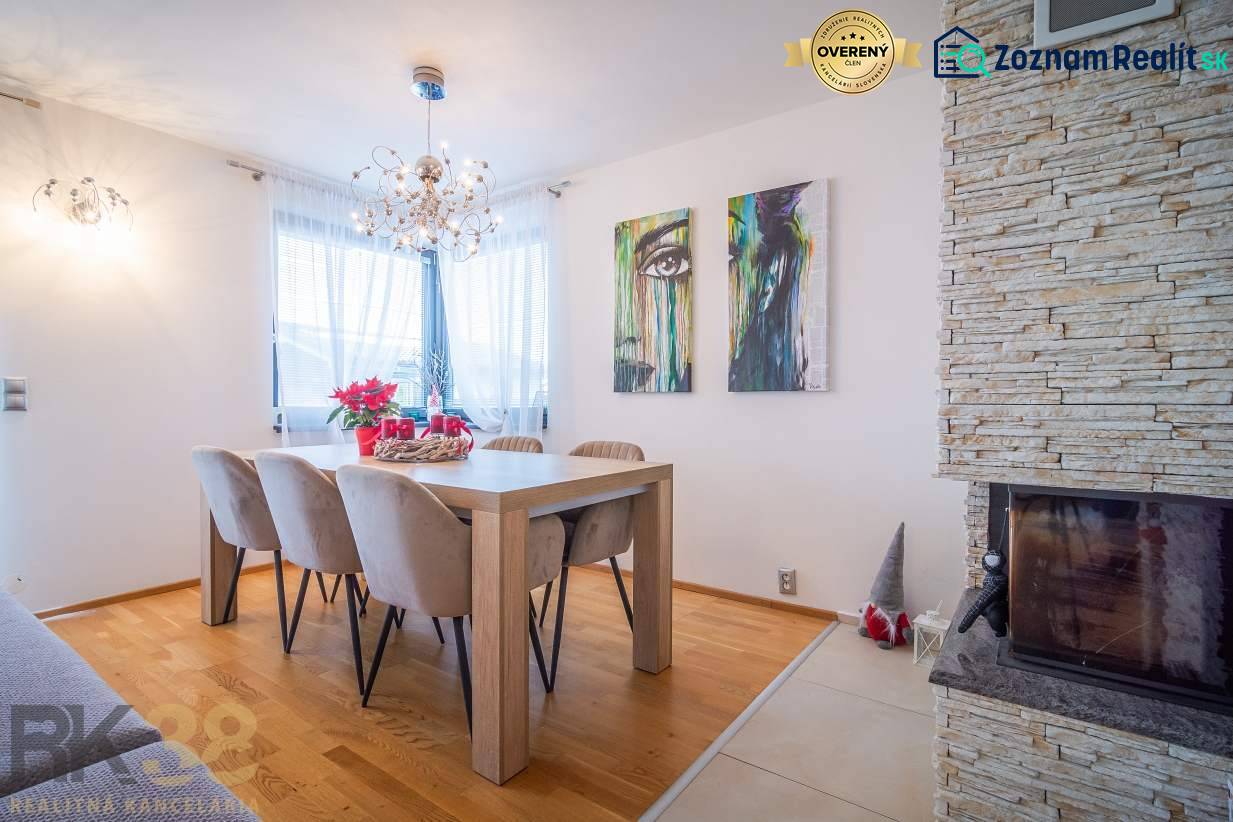 Dining room in a family house with a wood-patterned floor, a fireplace, and wall art.