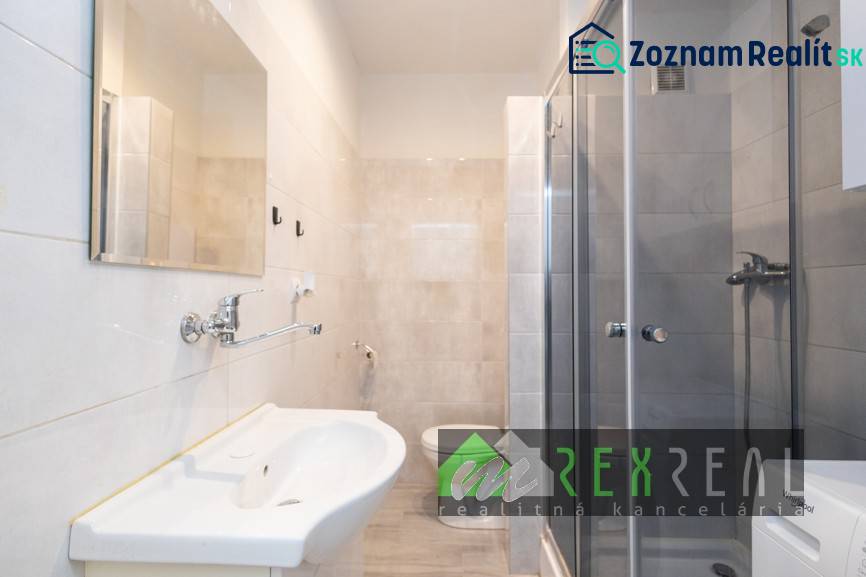 Bathroom in a 3-room apartment with a shower, sink, and light tiles.