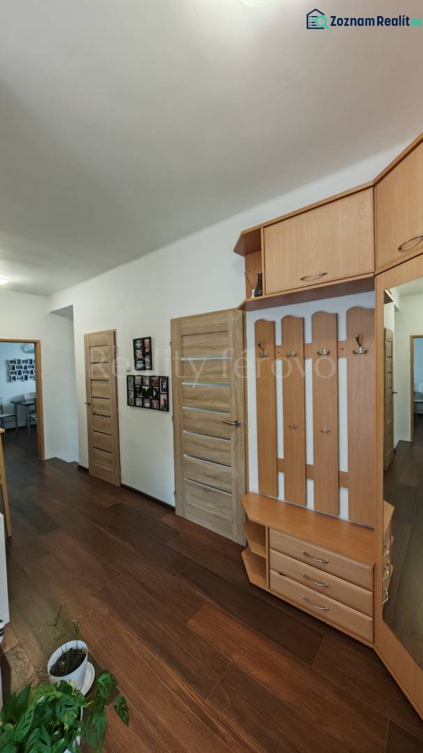 A hallway in a family house with a wooden decor floor, coat racks, and a small bookshelf.