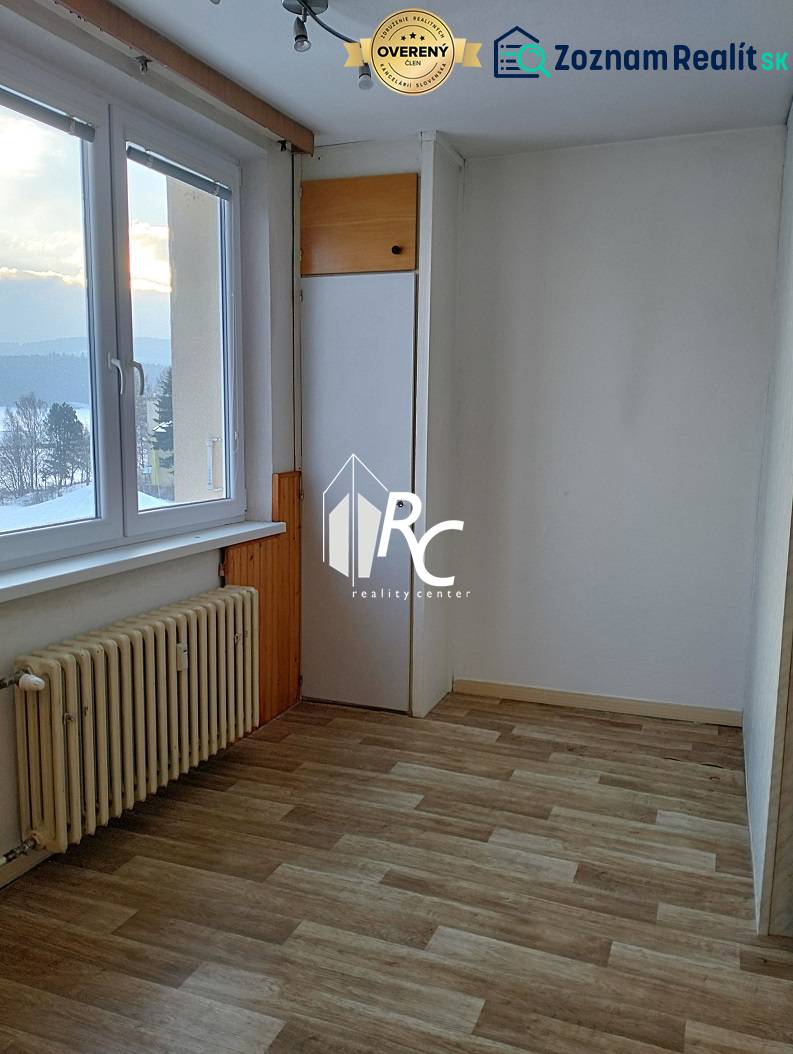 A bright room in a 2-room apartment with a wooden decor floor and a radiator.