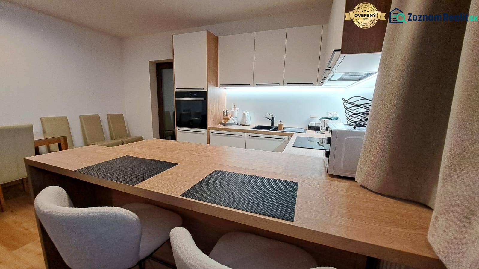 A kitchen in a 2-room apartment with built-in appliances and a wooden decor floor.