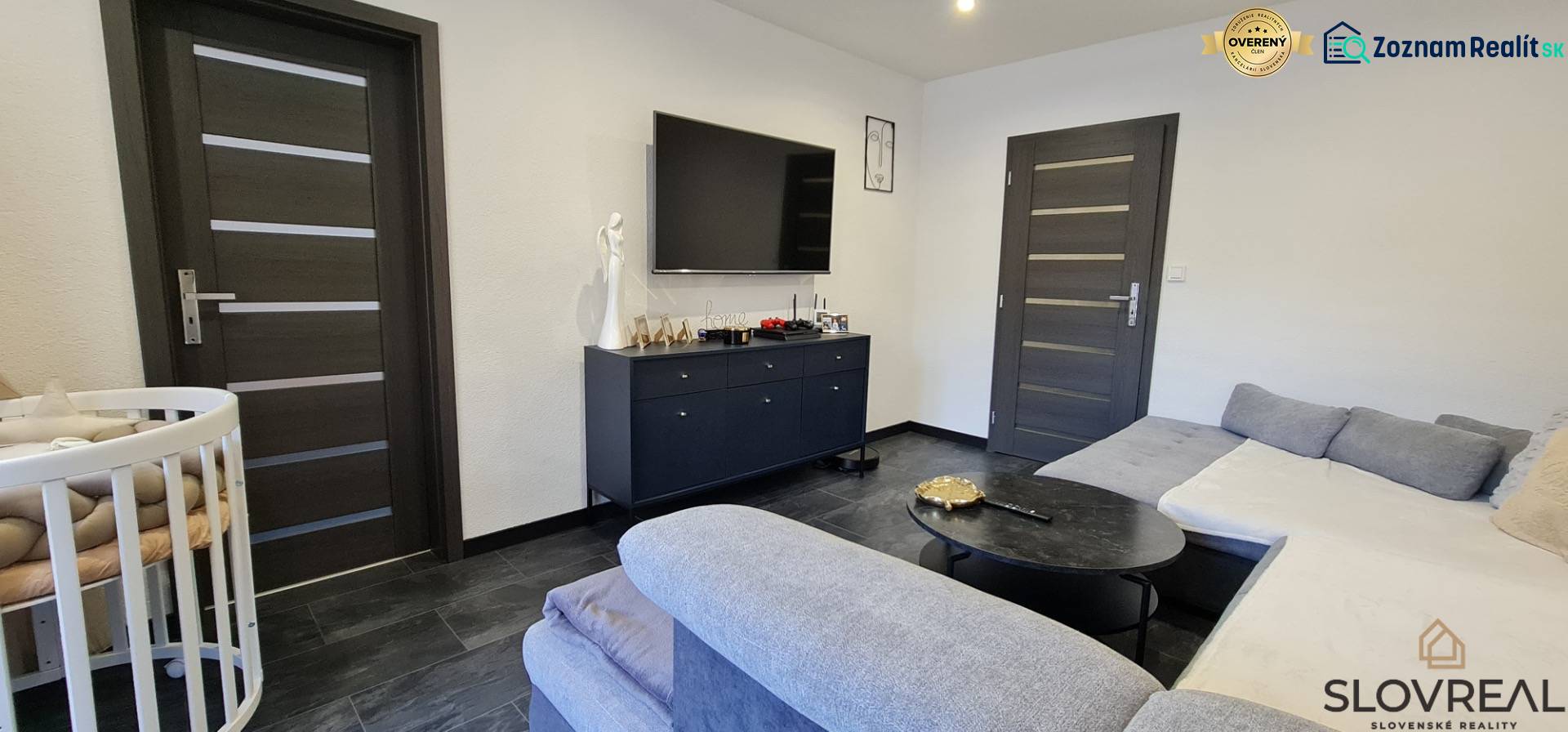 Living room in a two-room apartment with a dark floor and a sofa.