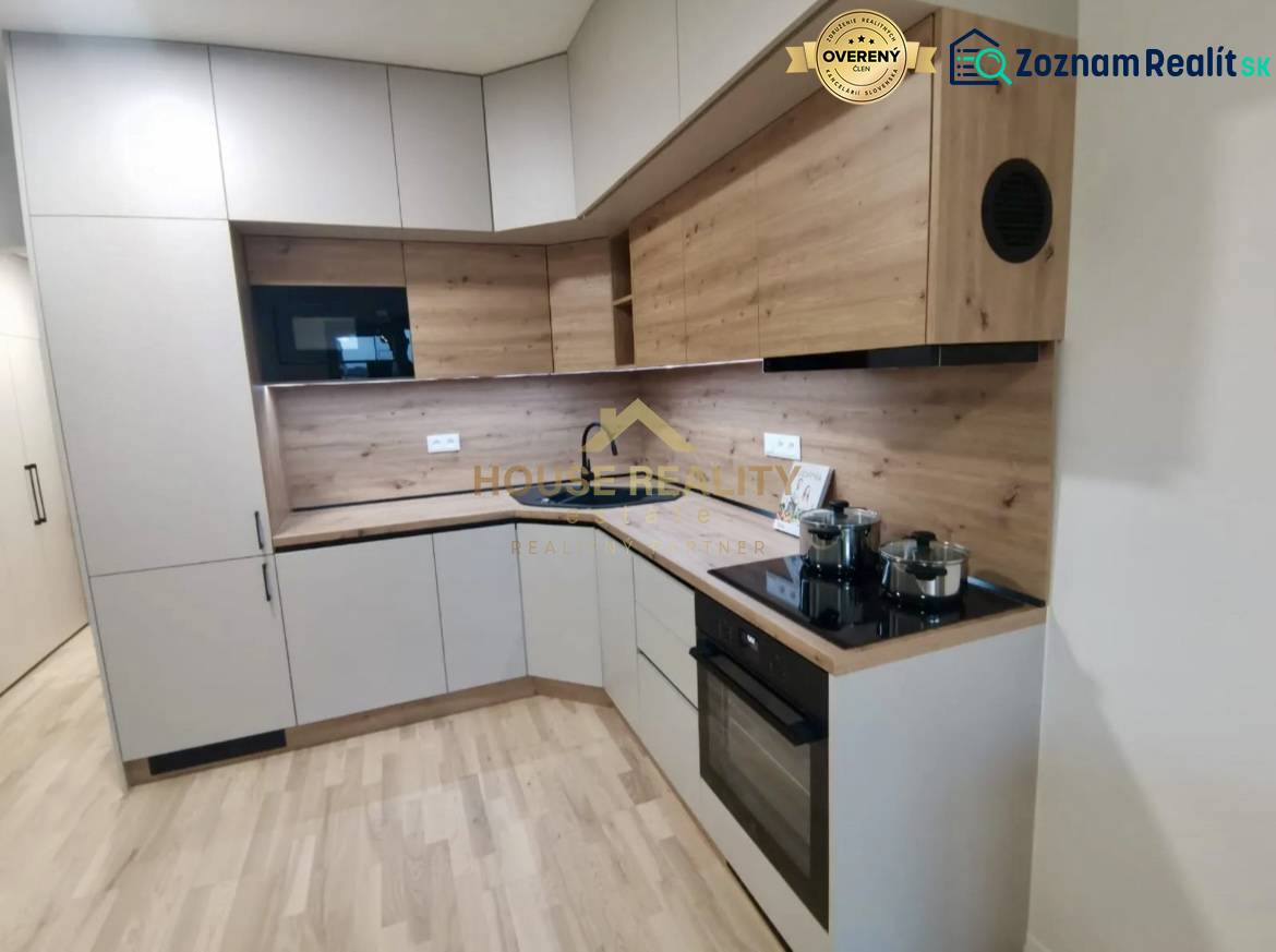 A kitchen in a studio apartment with a wooden decor floor and modern appliances.