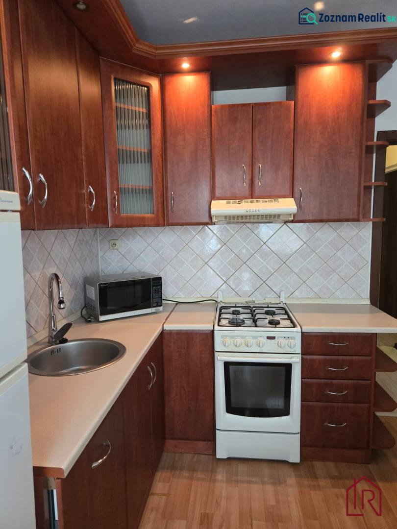 A kitchen in a 3-room apartment with a wood-decor floor and wooden cabinets.