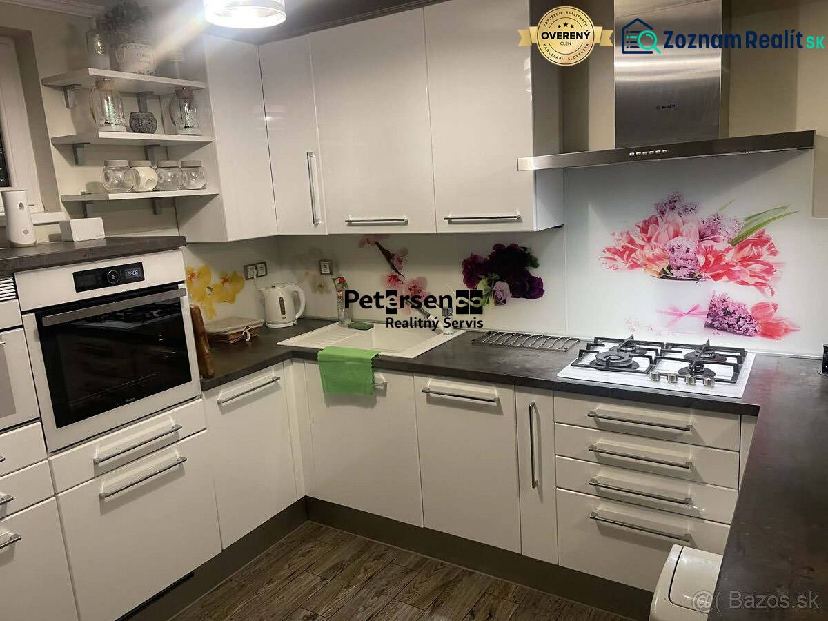 A kitchen in a family house with white cabinets, decorative tiles, and a wooden-patterned floor.