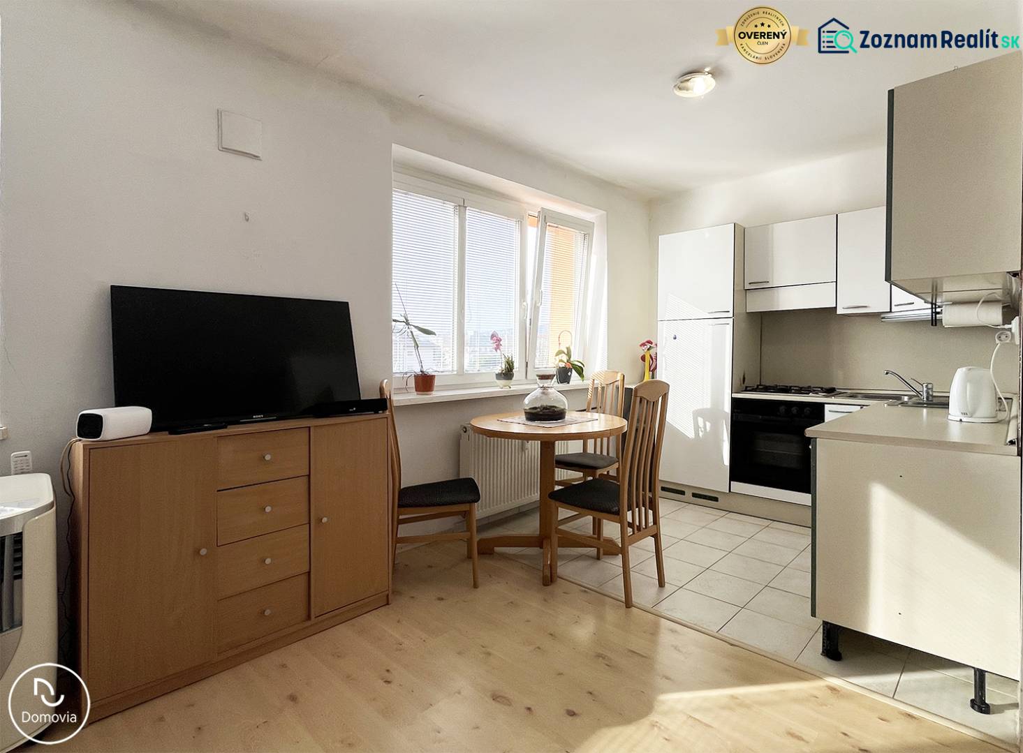 A kitchen with a dining table and a wooden decor floor in a studio apartment.