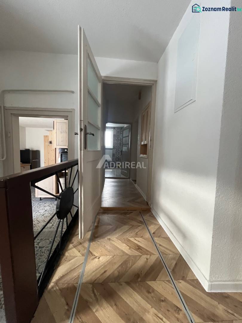 A hallway in a family house with a wooden decor floor and open doors.