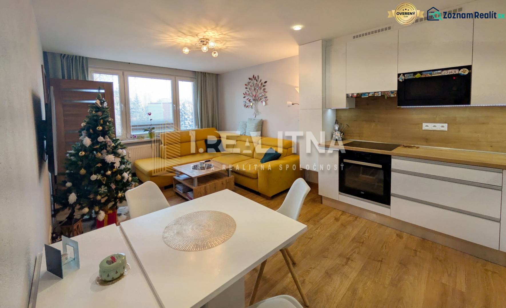 Living room in a three-room apartment with a wooden decor floor and a kitchen.