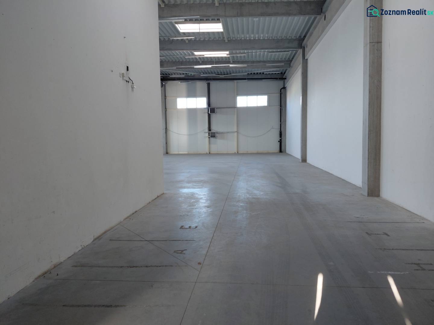 Empty interior of warehouses and halls with white walls and concrete floor.