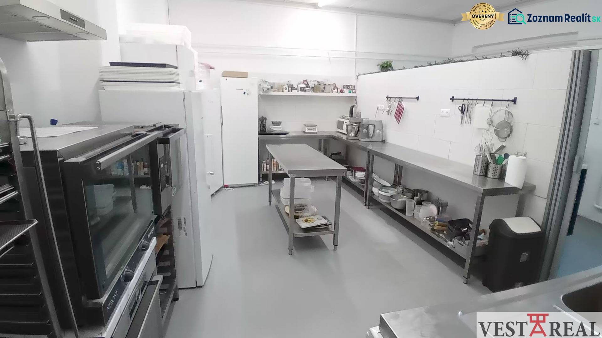Kitchen equipment in a warehouse hall with stainless steel furniture and appliances.