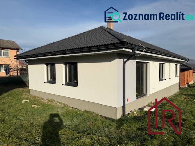 A family house in Bretejovce with a dark roof and a white facade, surrounded by a lawn.