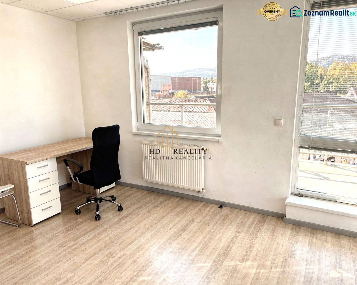 A workspace in a 2-room apartment with a wooden decor floor and a street view.