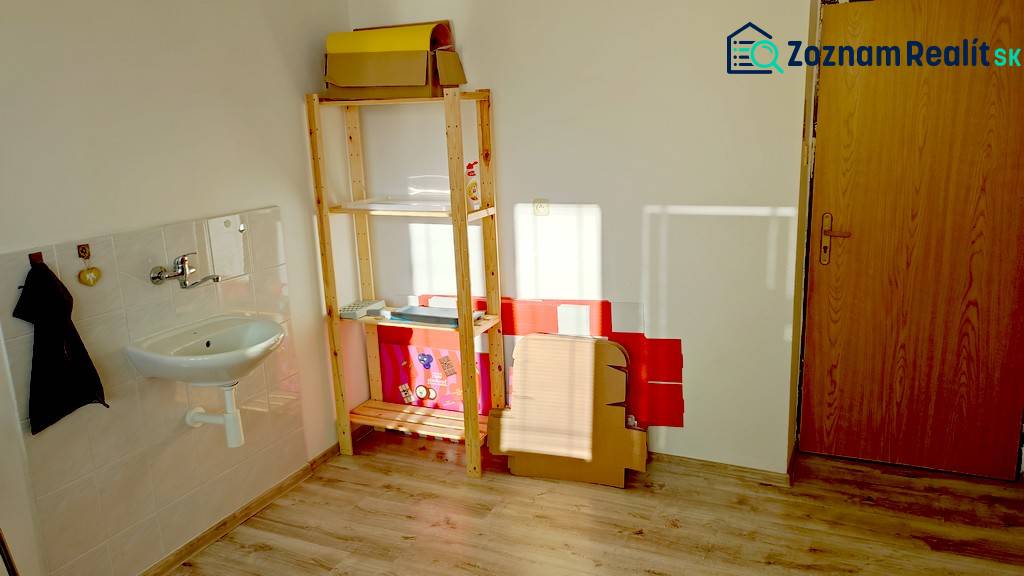 An office with a shelf, a sink, and a wooden decor floor.